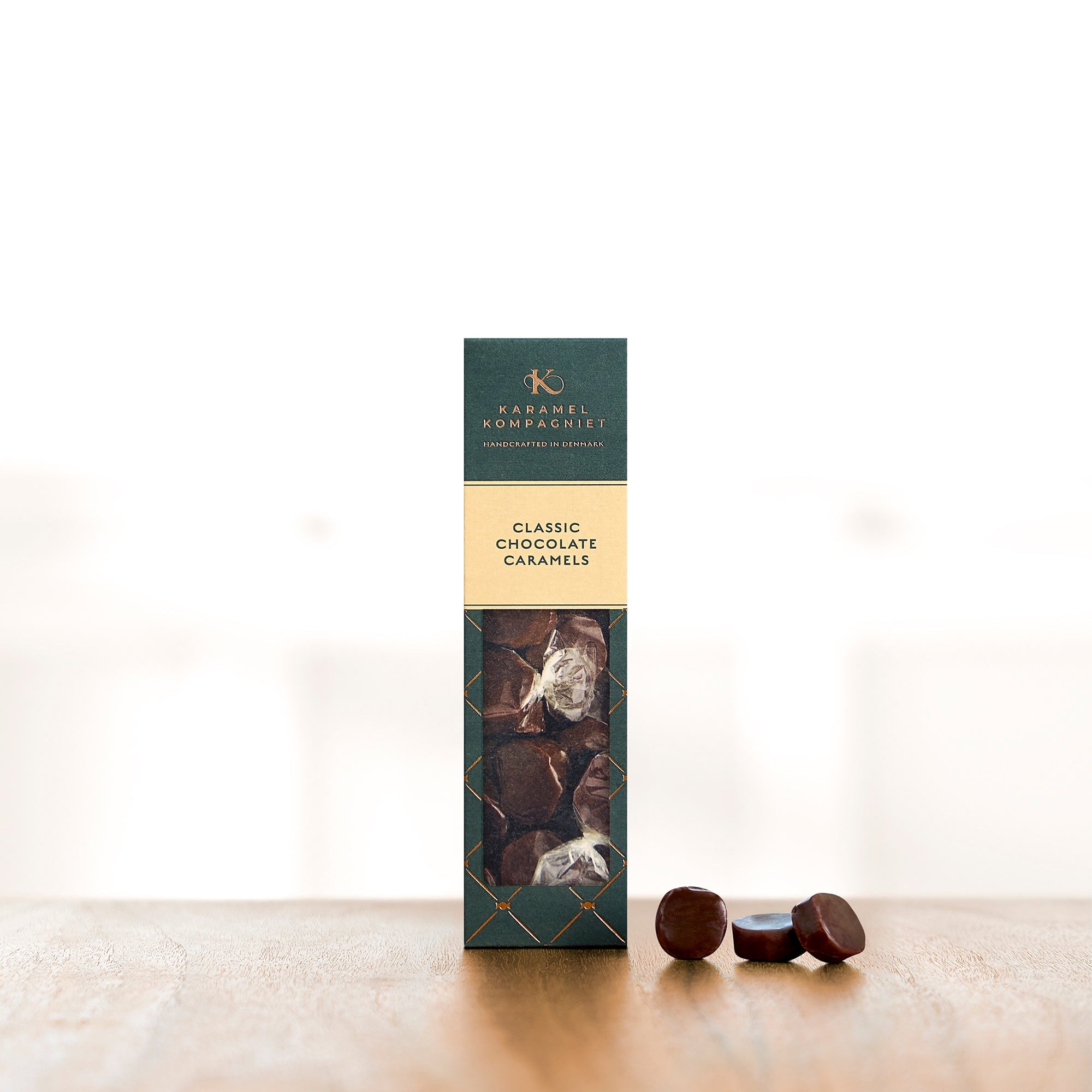 Chokoladekarameller i oprejst æske med tre karameller ved siden af
