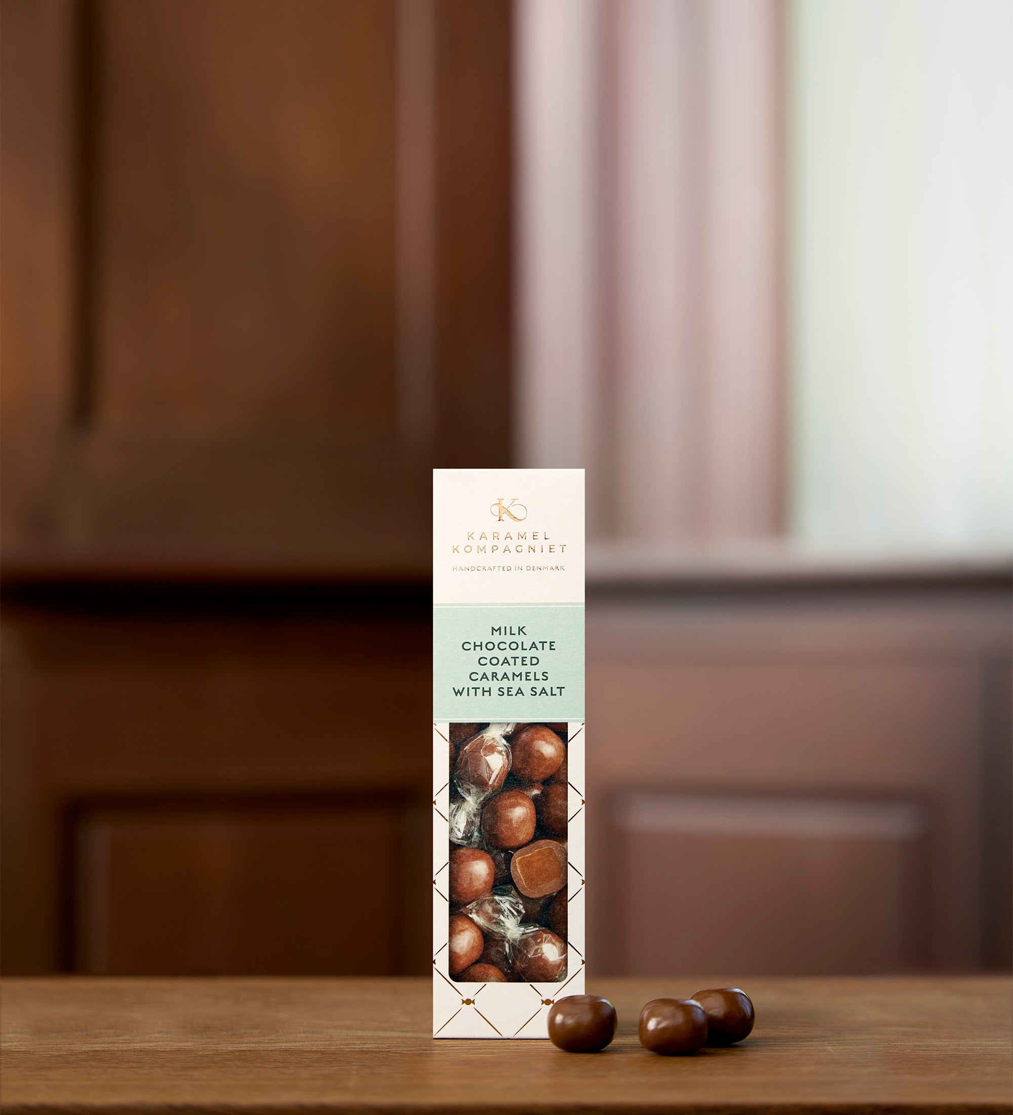 Milk Chocolate Coated Caramels with Sea Salt i hvid Elegance-æske fra Karamel Kompagniet der står på et bord – håndlavede chokoladekarameller fra Bornholm
