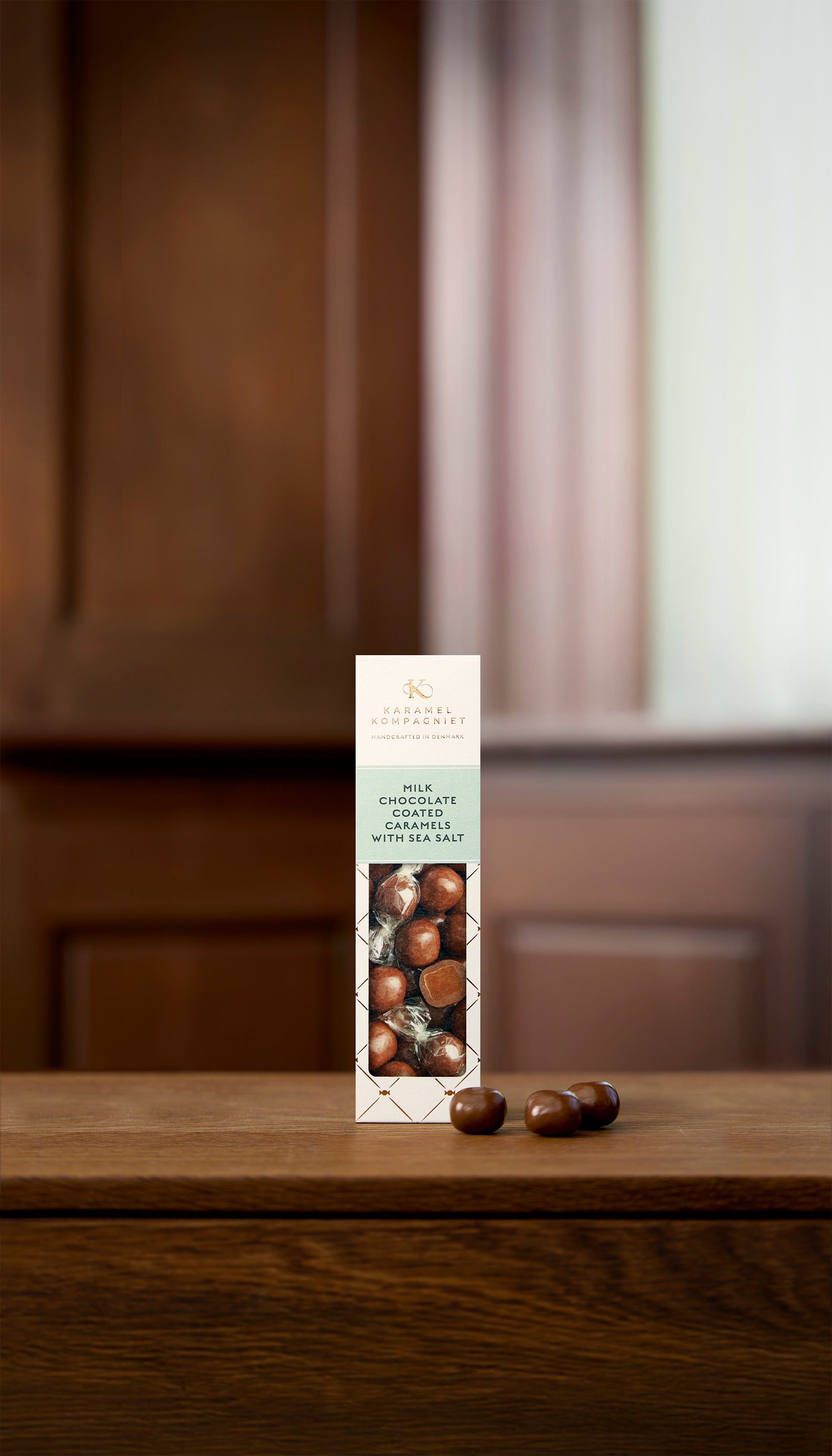 Milk Chocolate Coated Caramels with Sea Salt i hvid Elegance-æske fra Karamel Kompagniet der står på et bord – håndlavede chokoladekarameller fra Bornholm
