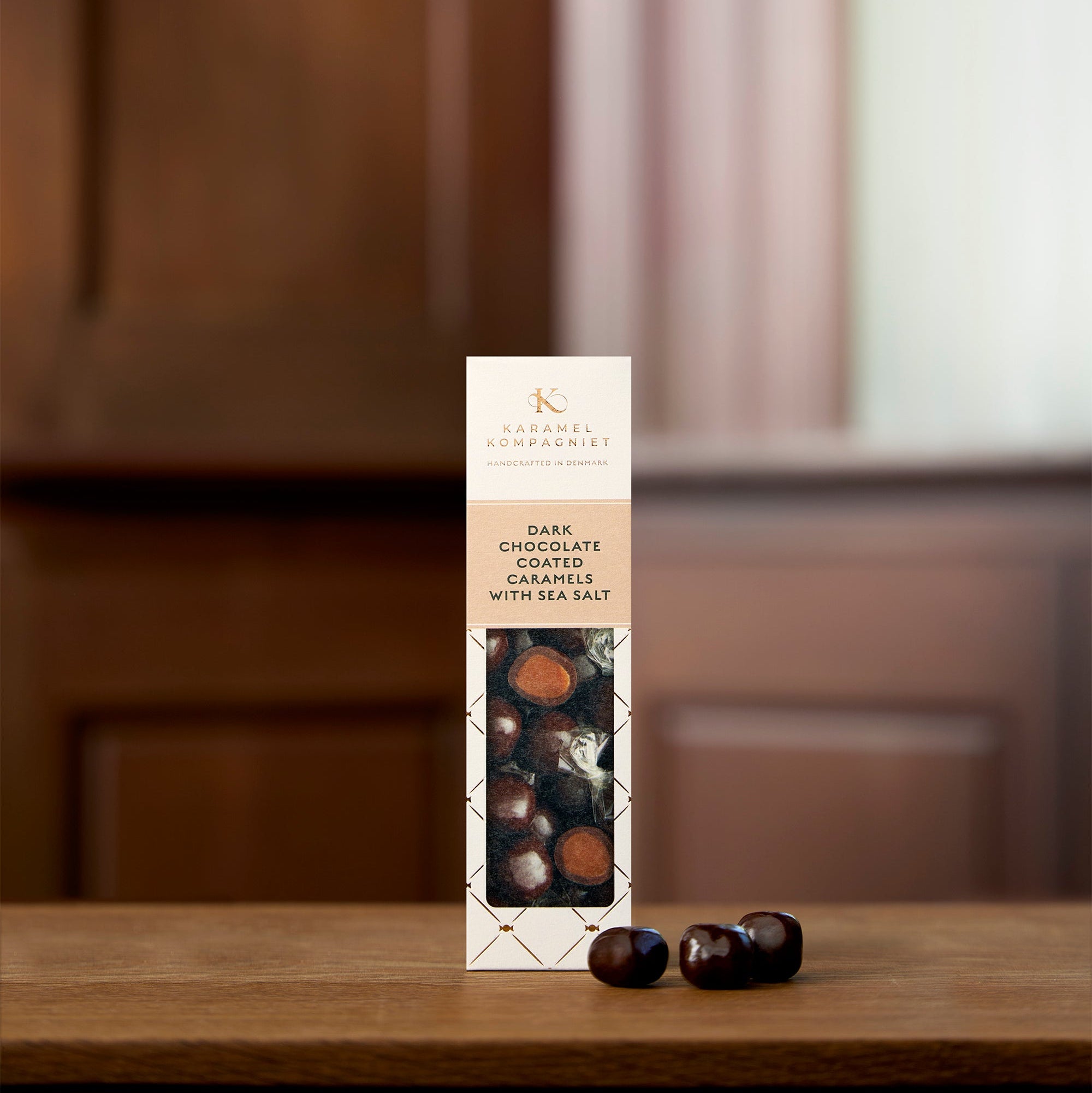 Chokoladeovertrukne saltkaramel kugler med mørk chokolade i oprejst E-æske der står på et bord