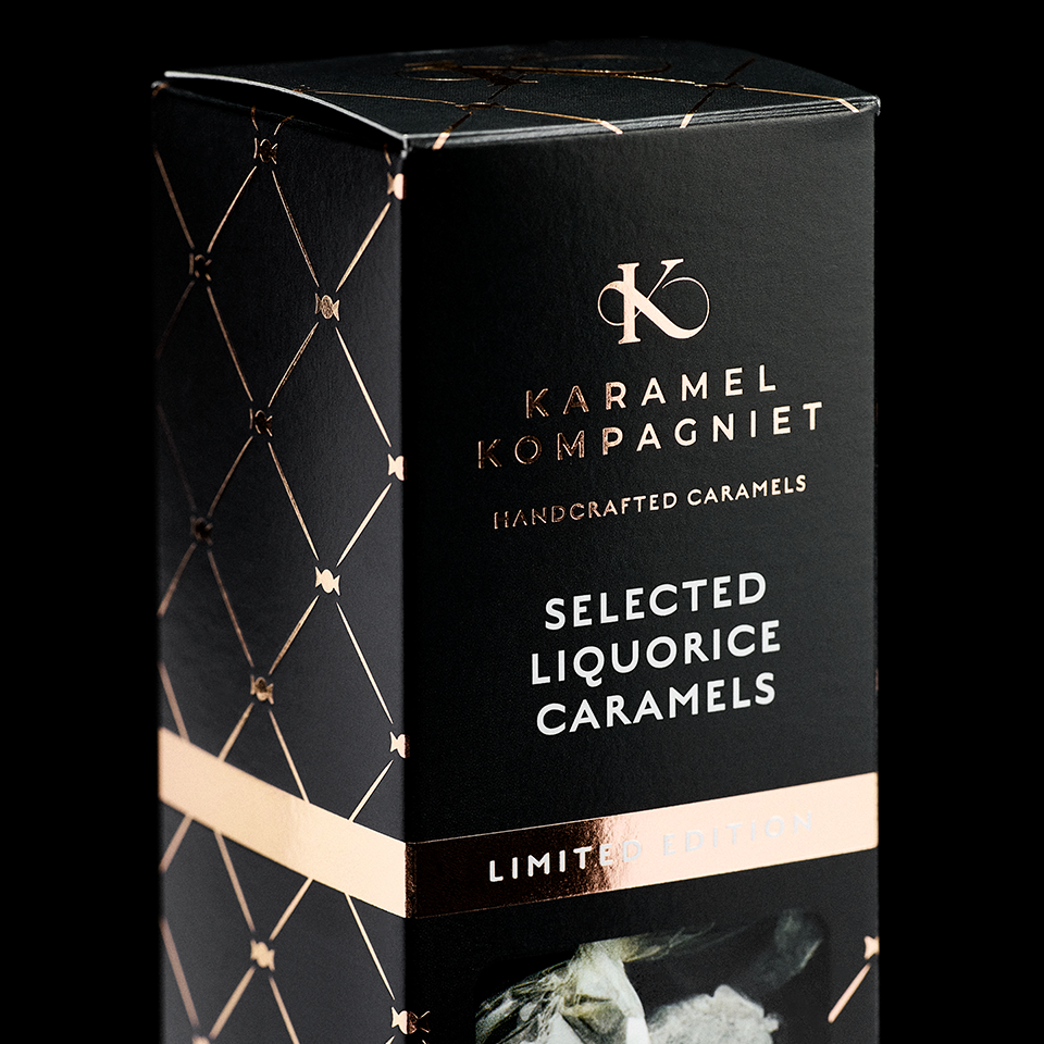 Nærbillede af Selected Liquorice Caramels Limited Edition-æske fra Karamel Kompagniet med guldtryk og rosegold detaljer på sort baggrund