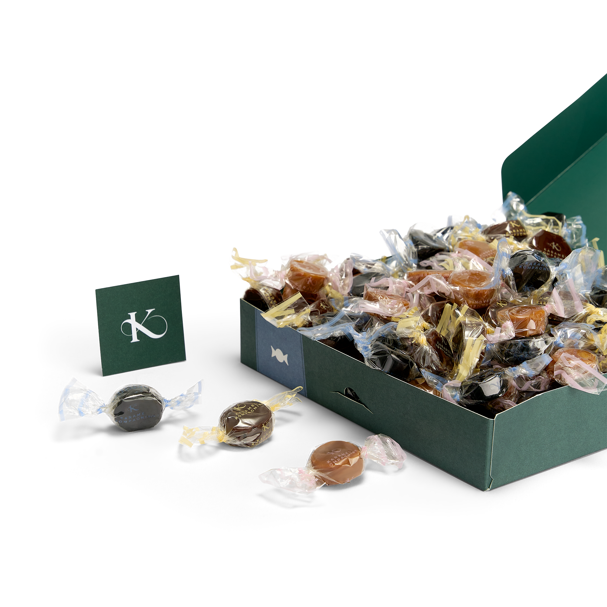 Gudhjem - Klassisk Karamelblanding med klassiske lakrids-, fløde- og chokoladekarameller i æske, der ligger ned med karameller, der flyder ud